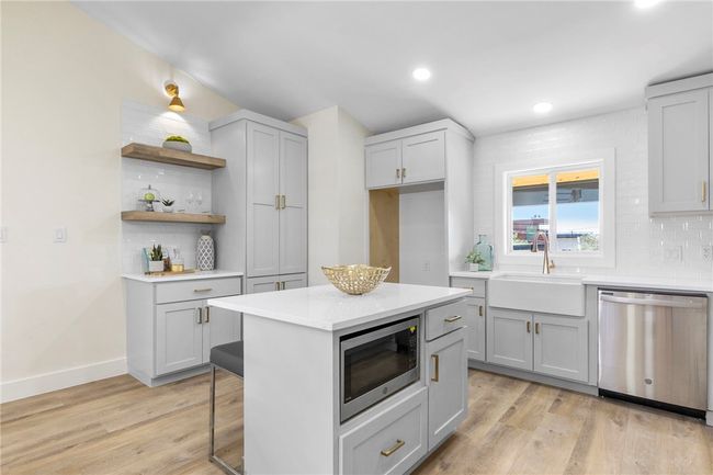 The dazzling kitchen boasts light grey shaker-style cabinetry accentuated with trendy gold hardware and sparkling quartz countertops. | Image 13