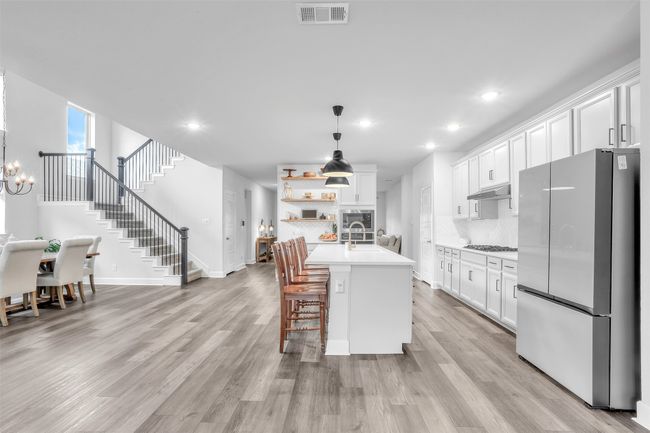 Kitchen featuring pendant lighting, stainless steel appliances, a center island with sink, and white cabinets | Image 13