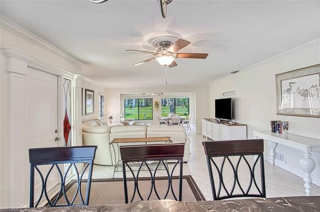 Living area with crown molding, a ceiling fan, visible vents, and baseboards | Image 19