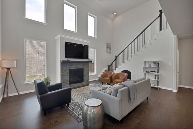 Living room featuring stairs, dark wood-style flooring, baseboards, a towering ceiling, and a stone fireplace | Image 7