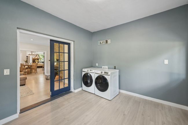 Washroom featuring washer and dryer, light wood-type flooring, baseboards, and french doors | Image 27