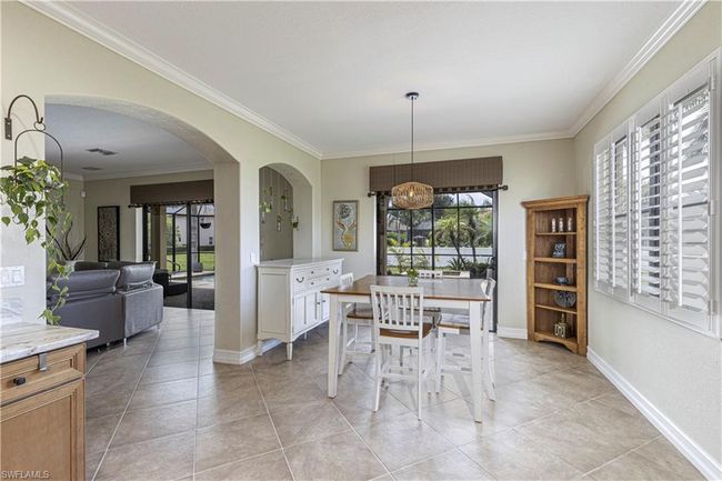 Dining room with light tile patterned flooring, arched walkways, baseboards, and ornamental molding | Image 11