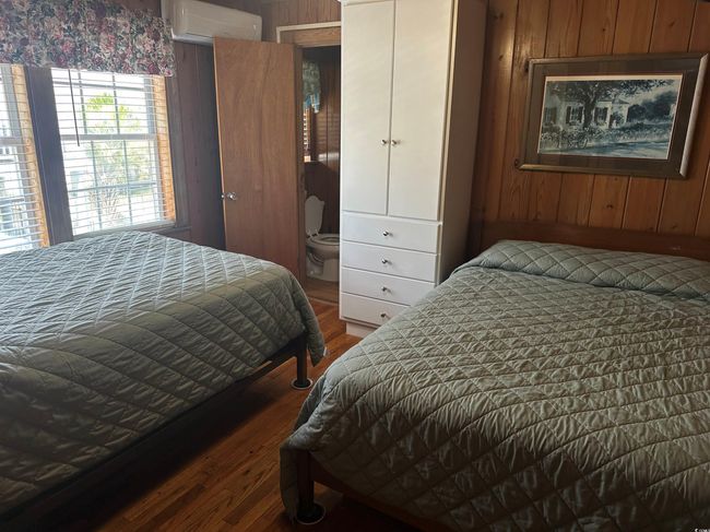 Bedroom with a wall unit AC, wood finished floors, and wooden walls | Image 22