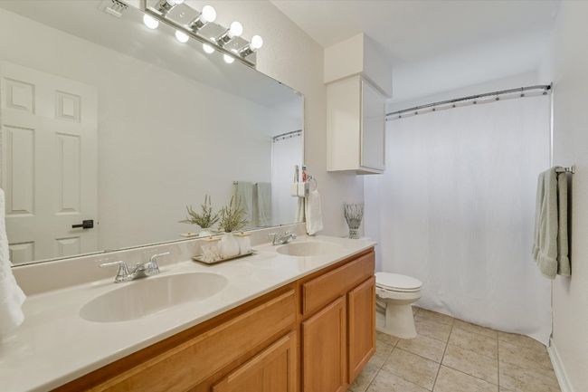 Full bath featuring double vanity, toilet, tile patterned flooring, and a shower with curtain | Image 23