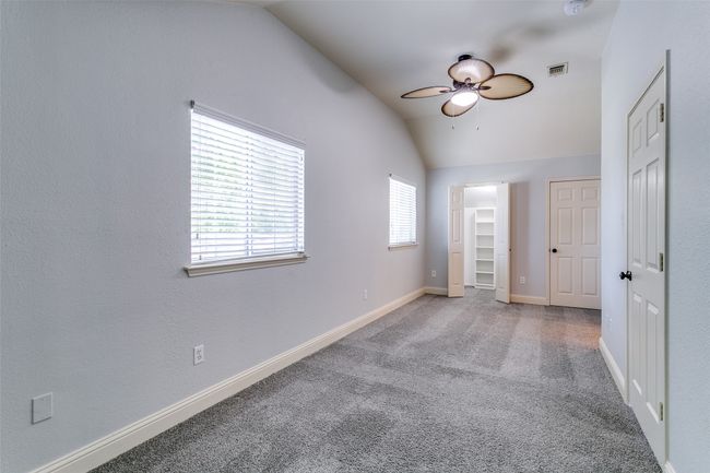 Unfurnished bedroom with vaulted ceiling, carpet, a spacious closet, and a ceiling fan | Image 22