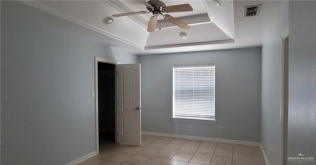 Spare room featuring a tray ceiling, ceiling fan, light tile patterned flooring, and baseboards | Image 5