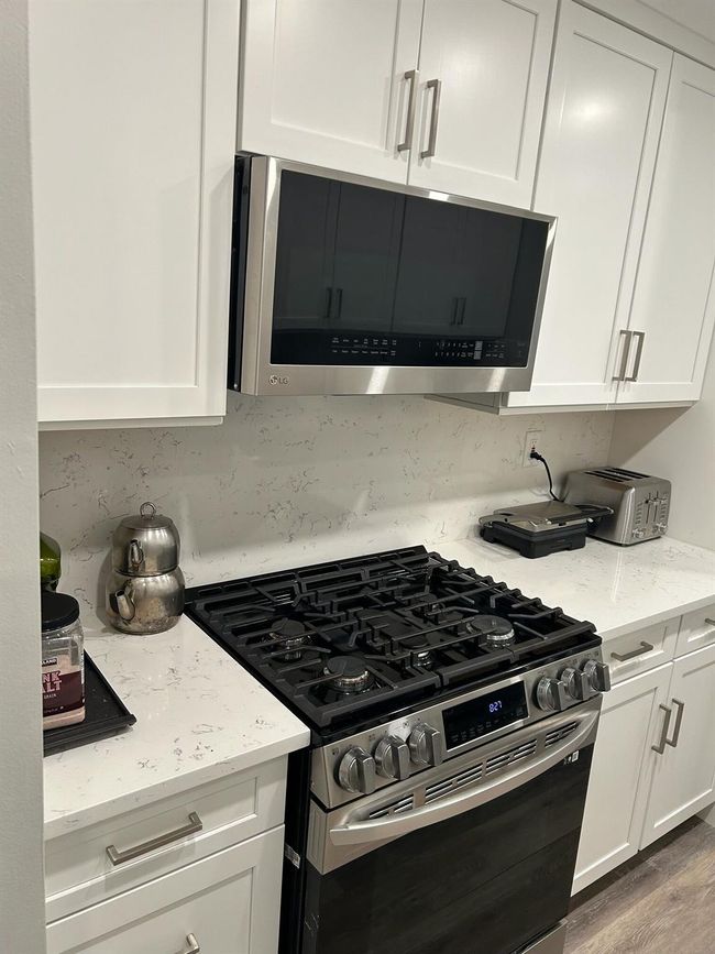 Kitchen featuring appliances with stainless steel finishes, white cabinets, and light stone counters | Image 12