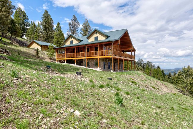 Back of house featuring stone siding and a wooden deck | Image 58