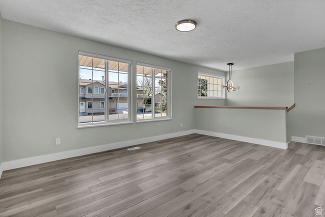 Interior space featuring an inviting chandelier, wood finished floors, visible vents, and a textured ceiling | Image 8