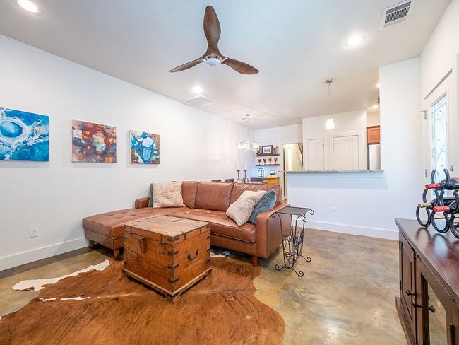 Living room with finished concrete flooring, ceiling fan, recessed lighting, and a chandelier | Image 13