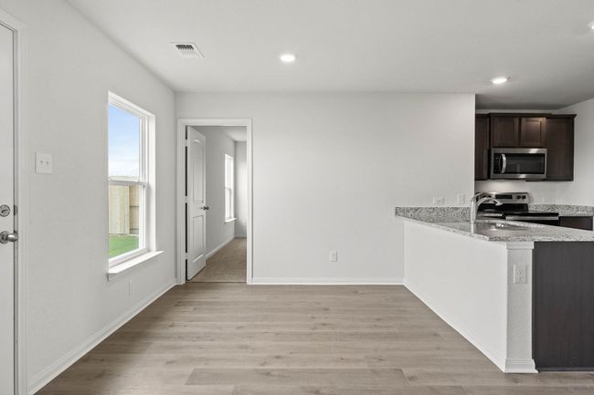 Kitchen featuring appliances with stainless steel finishes, light wood-style floors, dark brown cabinets, light stone countertops, and recessed lighting | Image 4