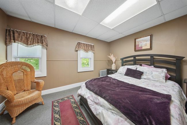 Bedroom with a drop ceiling, carpet floors, a wainscoted wall, radiator heating unit, and baseboards | Image 23