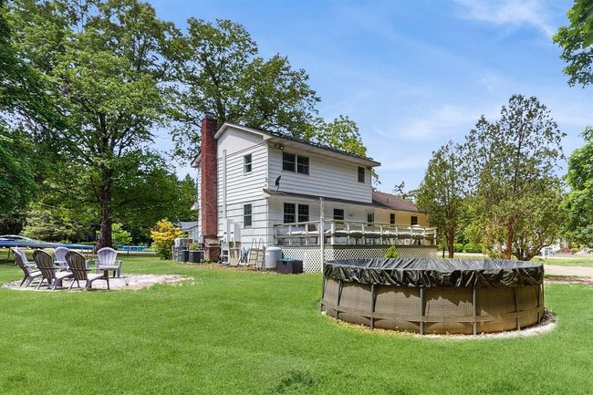 Back of house featuring an above ground pool, a very large yard, and a huge deck. | Image 40