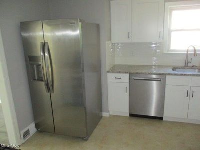 Kitchen with white cabinetry, light stone counters, sink, decorative backsplash, and appliances with stainless steel finishes | Image 2