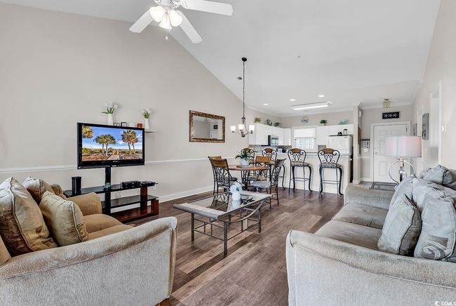 Living area featuring dark wood-style flooring, baseboards, recessed lighting, high vaulted ceiling, and ceiling fan with notable chandelier | Image 11