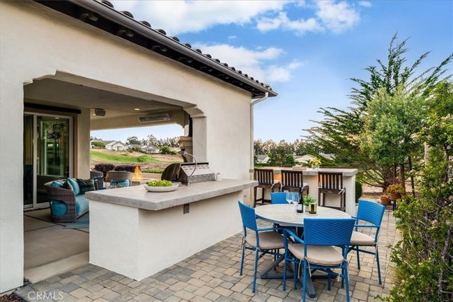 Outdoor kitchen with BBQ, Refrigerator, Cement stone top bar sitting area, fireplace and drop-down electric sun shade. | Image 43