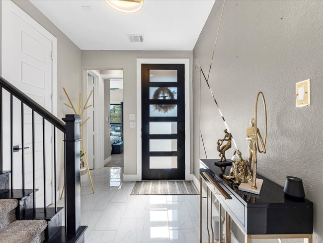 Welcome to this stunning modern Home! As you step inside, you are greeted by a chic entryway featuring an upgraded sleek black door with frosted glass panels for privacy and allowing natural light to pour into the house The foyer sets the tone with the polishing flooring adding a touch of elegance and leading you to a beautifully designed space | Image 5