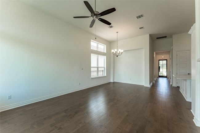 Empty room with healthy amount of natural light, dark wood-style flooring, ceiling fan, and a chandelier | Image 22