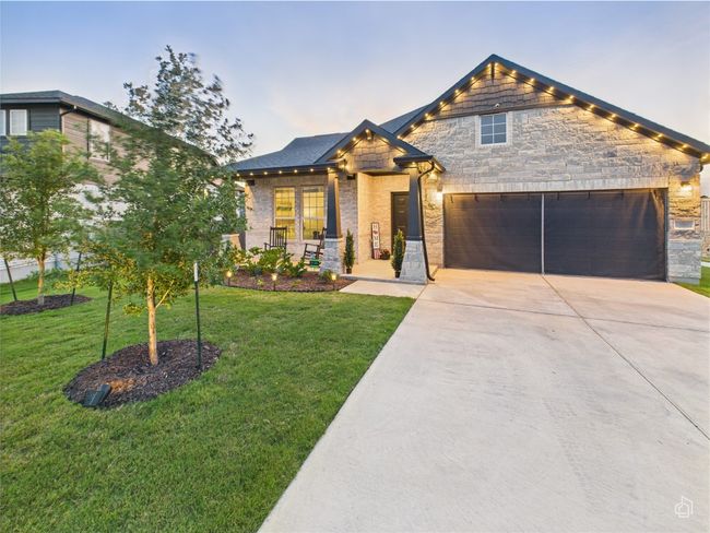 View of front facade with concrete driveway, a front yard, stone siding, and an attached garage | Image 5
