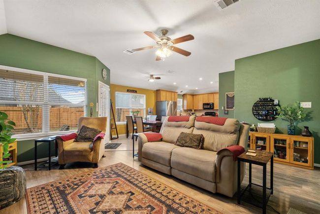 Living room features beautiful flooring, aceiling fan, custom paint, and large windows. | Image 8