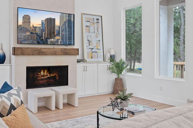 Living area with plenty of natural light, light wood-type flooring, and a warm lit fireplace | Image 6