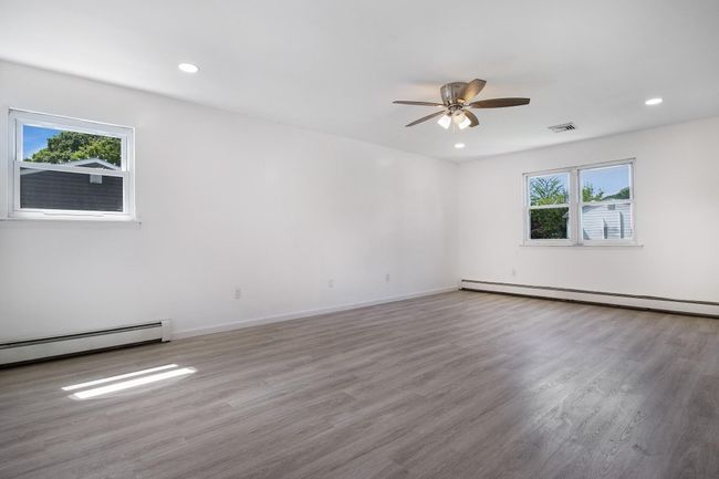 Unfurnished room featuring ceiling fan, baseboard heating, wood finished floors, recessed lighting, and a baseboard heating unit | Image 23