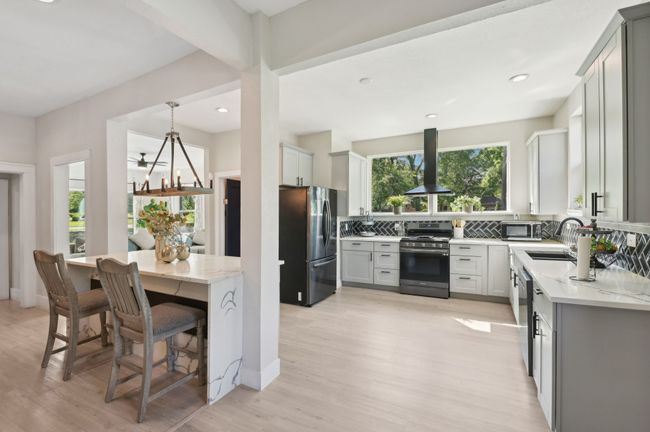 Kitchen featuring appliances with stainless steel finishes, extractor fan, a sink, light wood-style floors, and light stone counters | Image 14