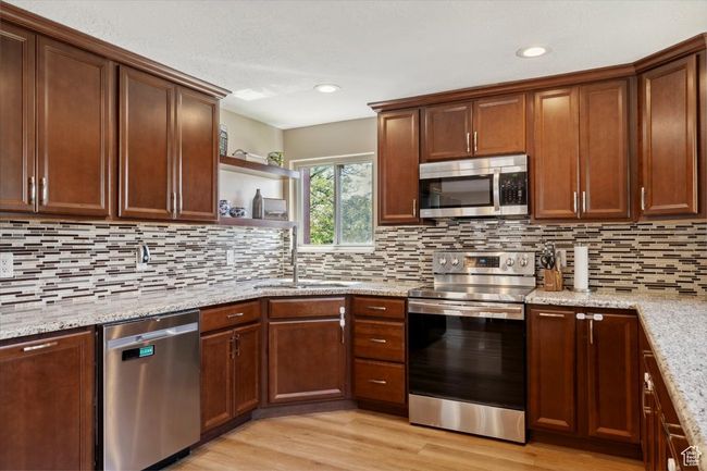 Kitchen with appliances with stainless steel finishes, granite countertops, wood LVP floors, recessed lighting, windows and backsplash | Image 8