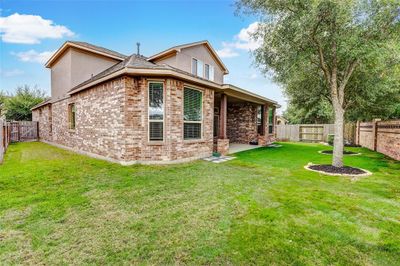 A sneak peak of the backyard highlights the homes beautiful elevation with brick on all sides, energy efficient windows, and large covered porch to enjoy your outdoor green space. | Image 1