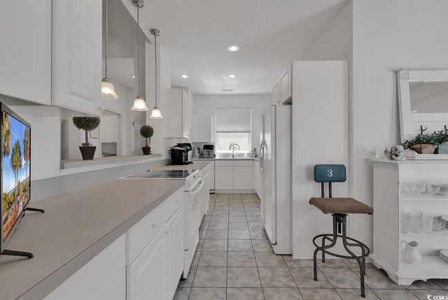 Kitchen with white appliances, white cabinets, light countertops, light tile patterned floors, and recessed lighting | Image 15
