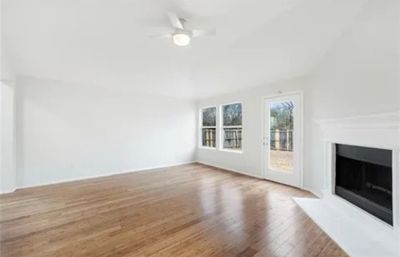 Unfurnished living room with wood-type flooring and ceiling fan | Image 3