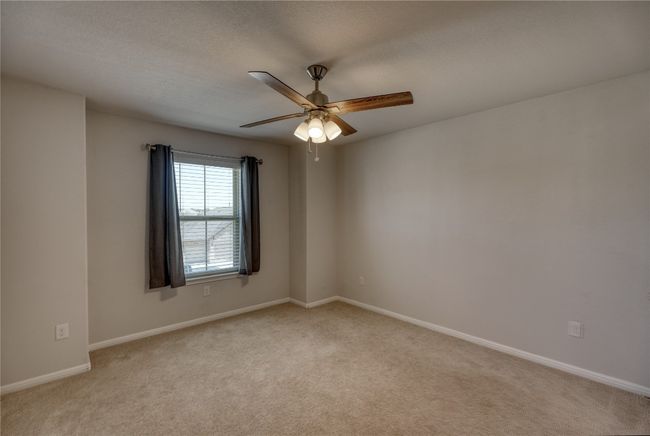 Empty room with light colored carpet, a textured ceiling, baseboards, and ceiling fan | Image 26