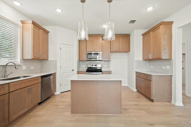 Kitchen with appliances with stainless steel finishes, backsplash, light countertops, light wood-style flooring, and recessed lighting | Image 6