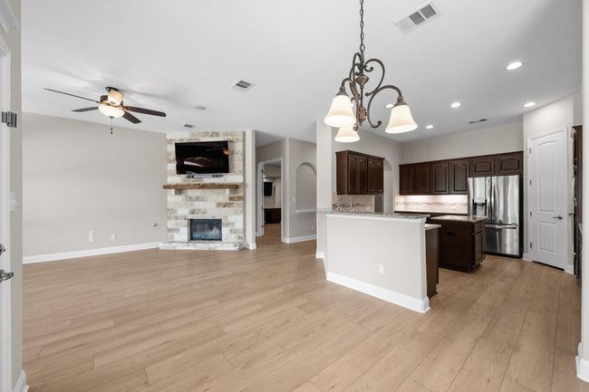 Kitchen with stainless steel fridge with ice dispenser, open floor plan, ceiling fan, dark brown cabinets, and a chandelier | Image 12