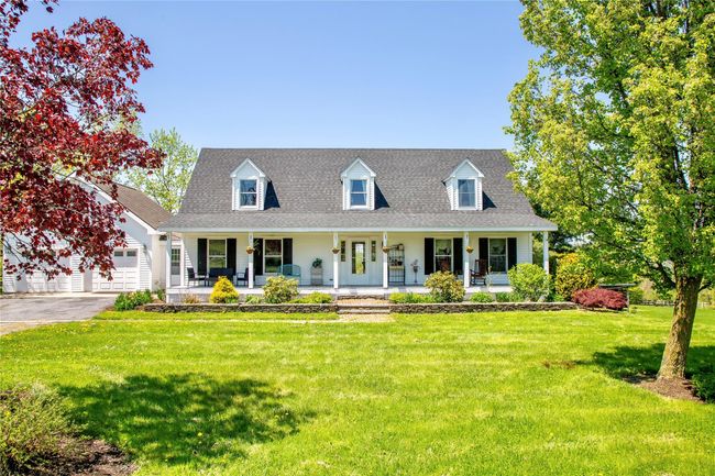 Cape cod home featuring a porch, a front lawn, a garage, and a shingled roof | Image 23