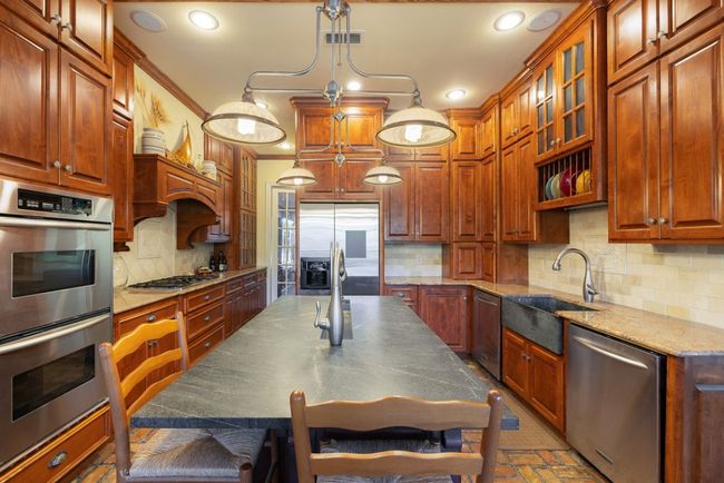 Kitchen featuring recessed lighting, a kitchen breakfast bar, a sink, decorative backsplash, and appliances with stainless steel finishes | Image 22