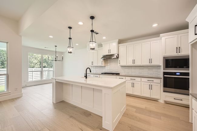 Kitchen featuring appliances with stainless steel finishes, under cabinet range hood, tasteful backsplash, recessed lighting, and light wood-style flooring | Image 12
