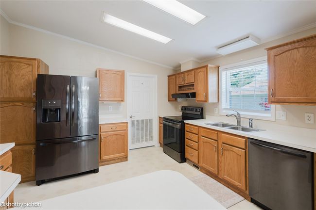 Kitchen featuring appliances with stainless steel finishes, vaulted ceiling, ornamental molding, light countertops, and light flooring | Image 4