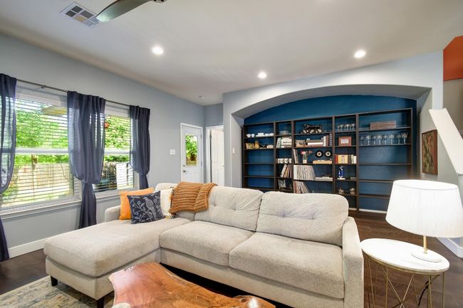 A sun-filled living area complete with a back wall of windows and engineered hardwood flooring throughout. | Image 6