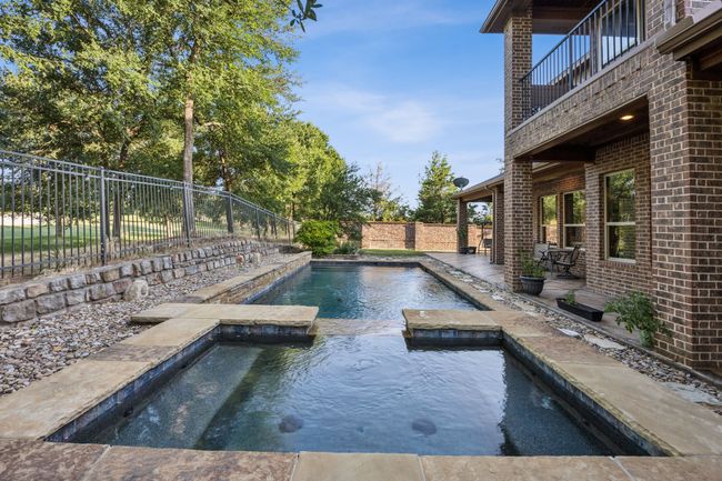 View of swimming pool with a fenced backyard and a pool with connected hot tub | Image 29