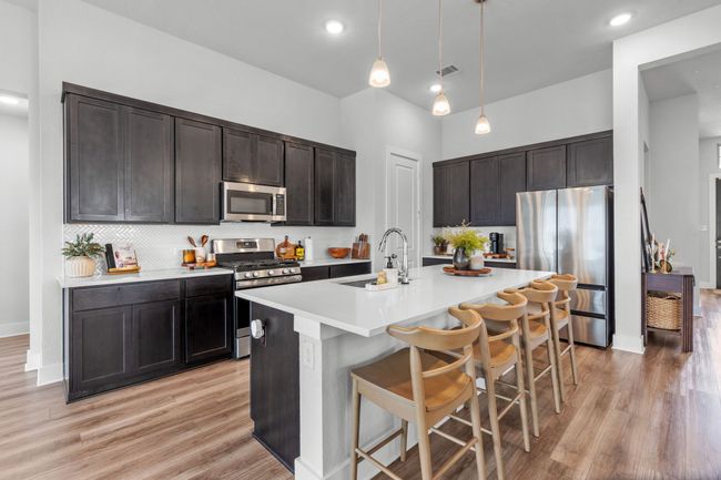 Kitchen featuring appliances with stainless steel finishes, a breakfast bar, pendant lighting, light wood-style flooring, and recessed lighting | Image 13