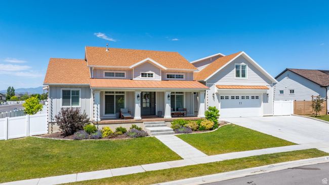 View of front of home with board and batten siding, a porch, a standing seam roof, concrete driveway, and a metal roof | Image 34