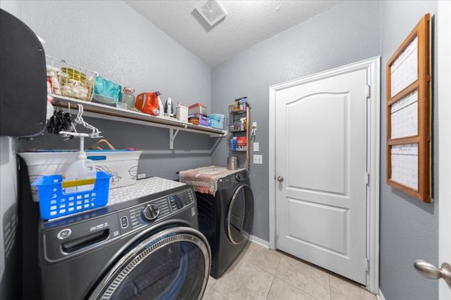 Laundry area featuring washing machine and clothes dryer, a textured ceiling, tile patterned flooring, and a textured wall | Image 11
