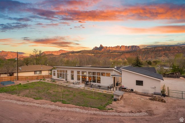 Back of property at dusk featuring a sunroom, a fenced backyard, stucco siding, a patio, and a mountain view | Image 61