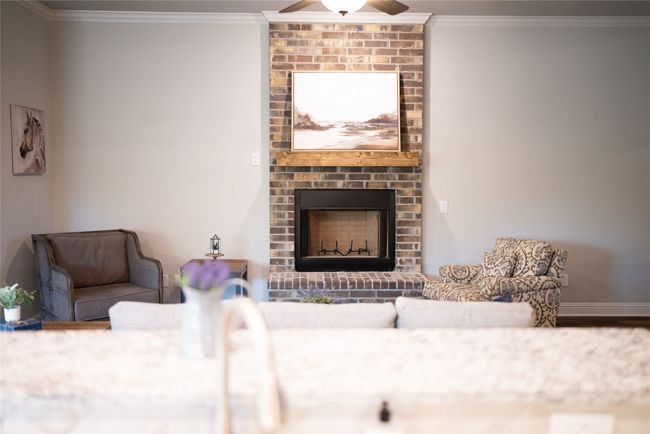 Living area featuring a fireplace, a ceiling fan, baseboards, ornamental molding, and wood finished floors | Image 6