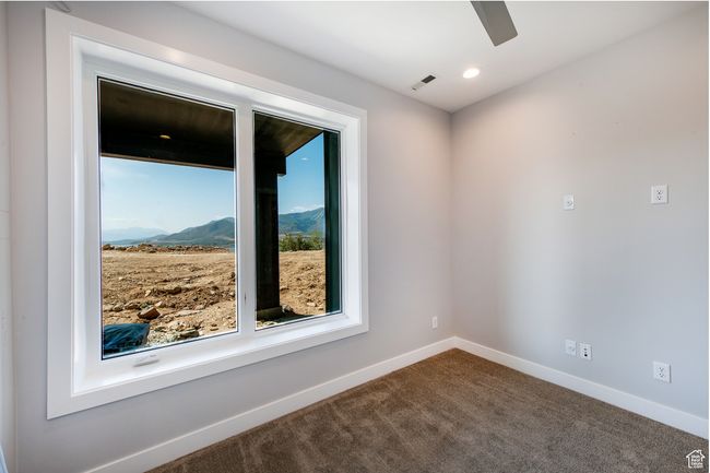 Carpeted empty room featuring a mountain view and ceiling fan | Image 12