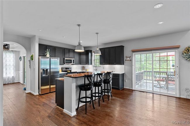 Kitchen with stainless steel appliances, dark wood-style flooring, arched walkways, and a kitchen island | Image 14