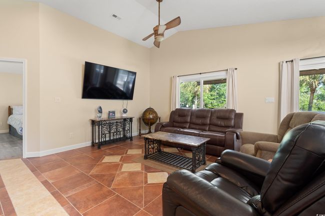 Living area featuring a ceiling fan, tile patterned floors, high vaulted ceiling, and baseboards | Image 18