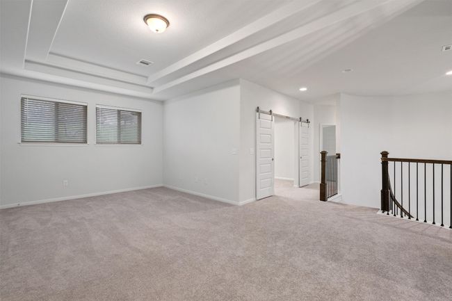 Empty room featuring a tray ceiling, recessed lighting, baseboards, a barn door, and light carpet | Image 24