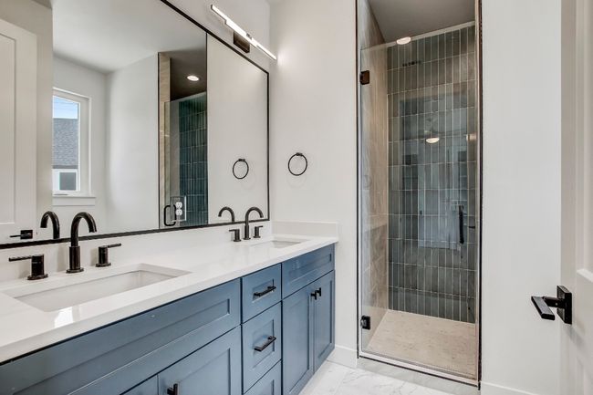 Bathroom with double vanity, marble finish flooring, a stall shower, and baseboards | Image 17